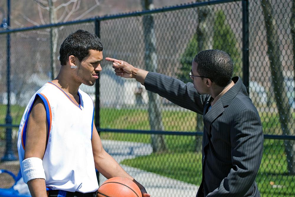 Coach pointing upset at a basketball player outdoors on the court.