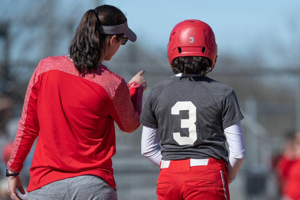 Softball coach talking to young player.