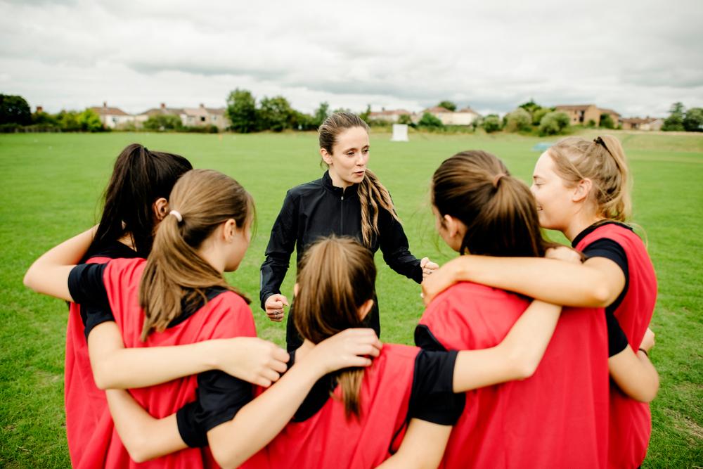 Female coach talking to teen soccer team.