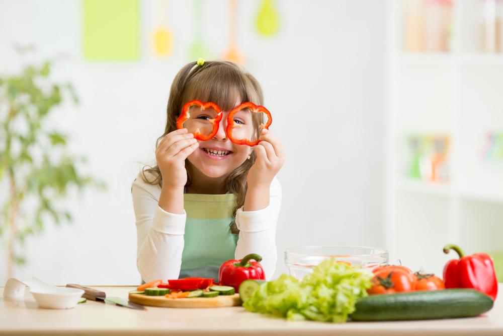 Young girl looking through sliced red peppers.
