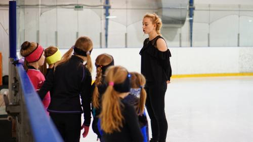 Female coach with ice skating students.