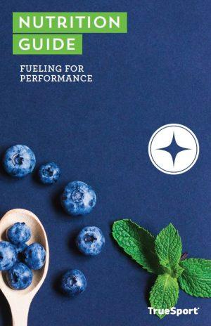 TrueSport Nutrition Guide: Fueling for Performance cover image of blueberries on a wooden spoon.