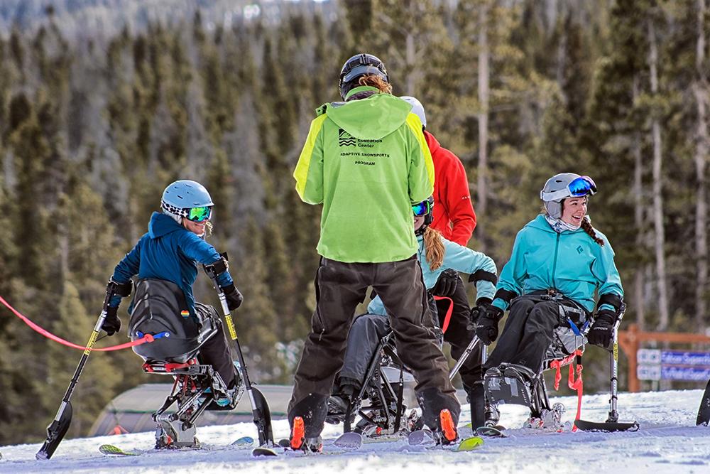 Small group of women adaptive skiing.